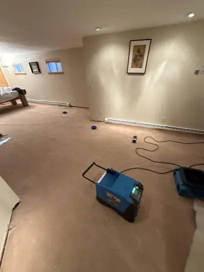 Finished basement with carpet pulled up and drying equipment running on the bare floor