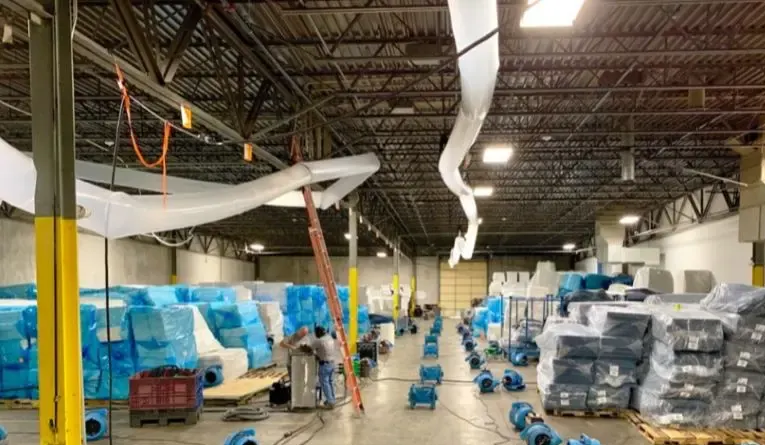Rows of air movers drying the concrete floor of a large commercial warehouse