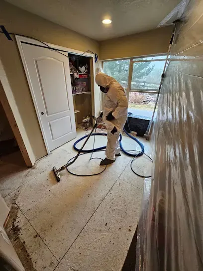 Technician in a protective suit extracting a contaminated floor in a gutted room